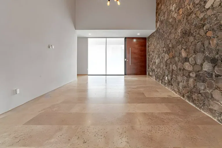 Casa Albero, entry hall with a stone wall, a tall wood front door and a travertine floor, San Miguel de Allende