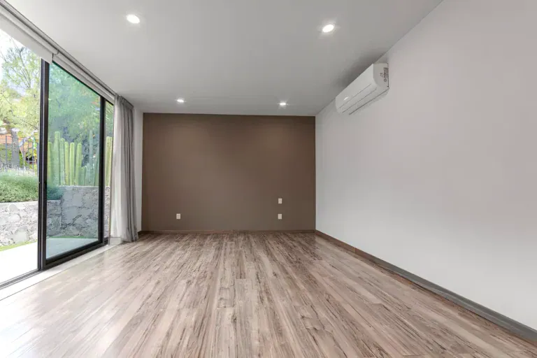 Casa Albero, empty bedroom with laminate flooring, a wall-mounted air conditioner and a sliding glass door to the garden, San Miguel de Allende