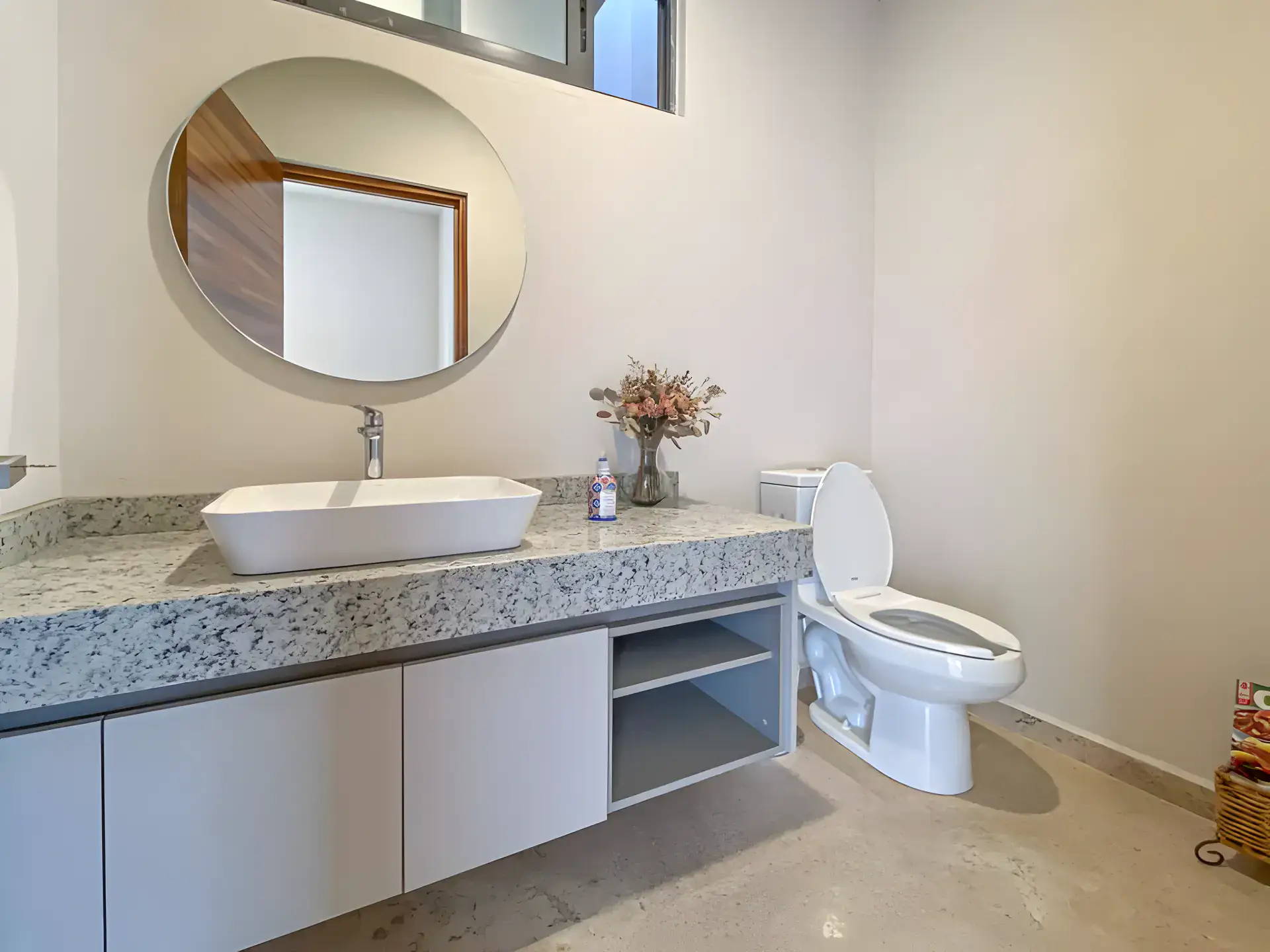 Casa Albero, bathroom with a round mirror, a vessel sink on a granite counter with a floating cabinet and a toilet, San Miguel de Allende