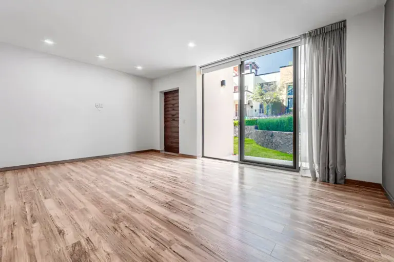 Casa Albero, empty bedroom with laminate flooring and a sliding glass door to the lawn, San Miguel de Allende