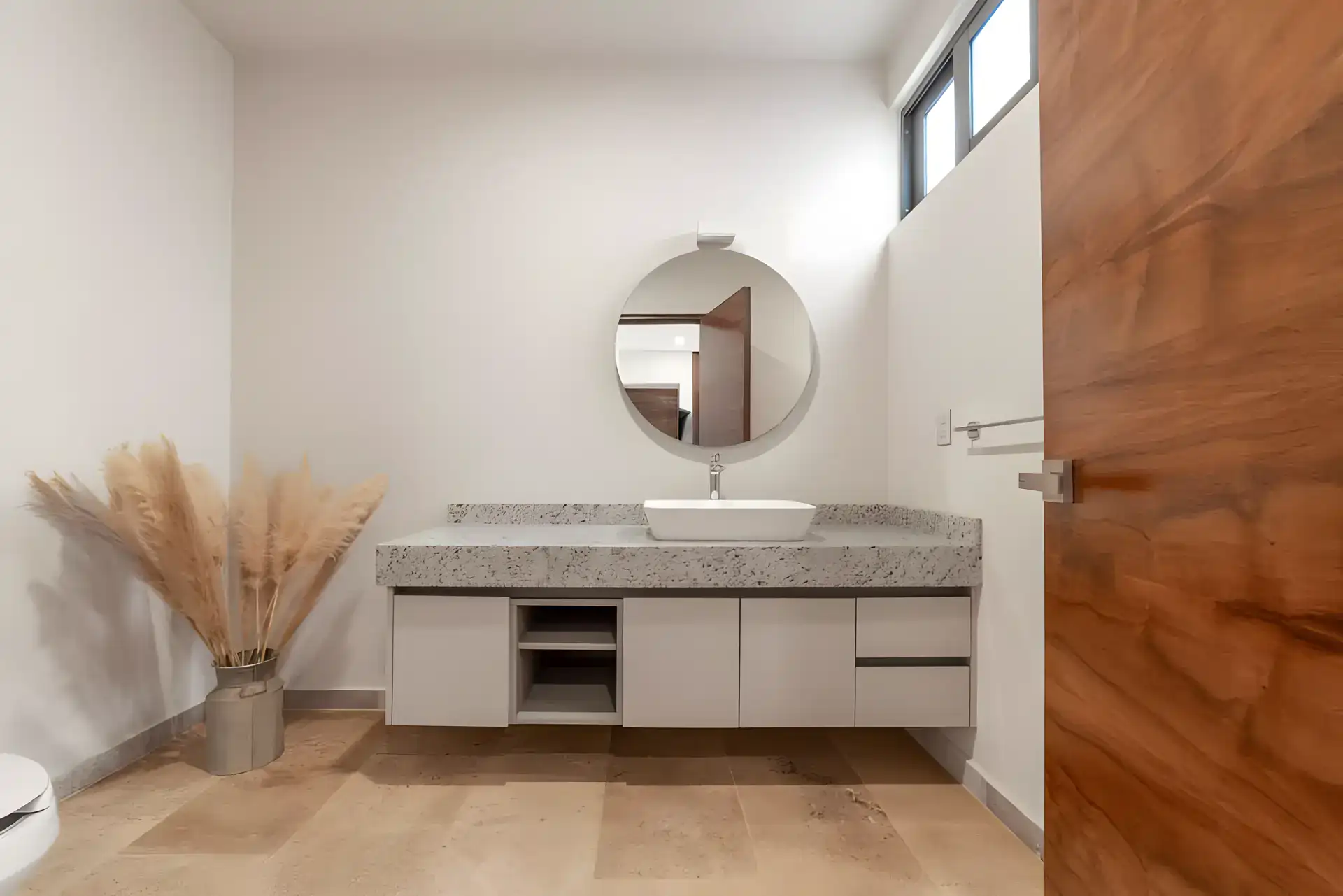 Casa Albero, bathroom with a floating vanity, a round mirror and pampas grass in a vase, San Miguel de Allende