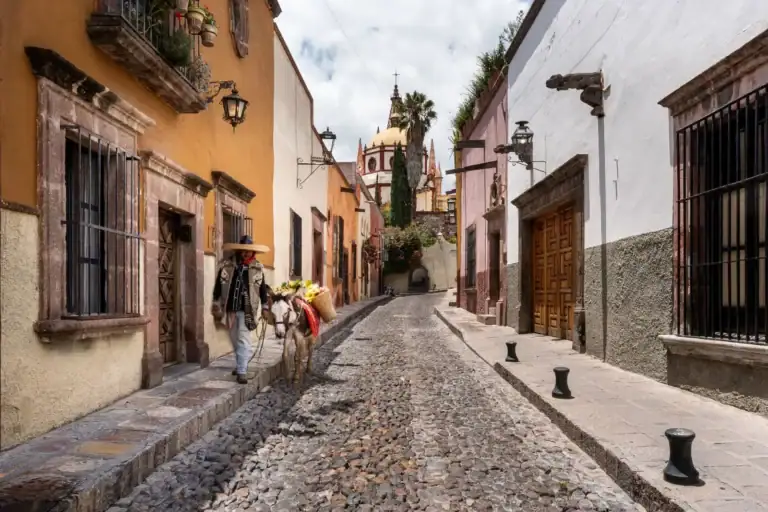 Casa Aldama, cobblestone Aldama street leading toward the Parroquia spires with a man and a donkey, San Miguel de Allende