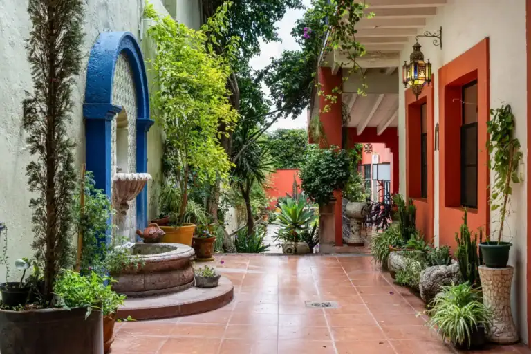 Casa Aldama, courtyard with a tiled fountain, a blue arch, tropical plants and terracotta floors, San Miguel de Allende