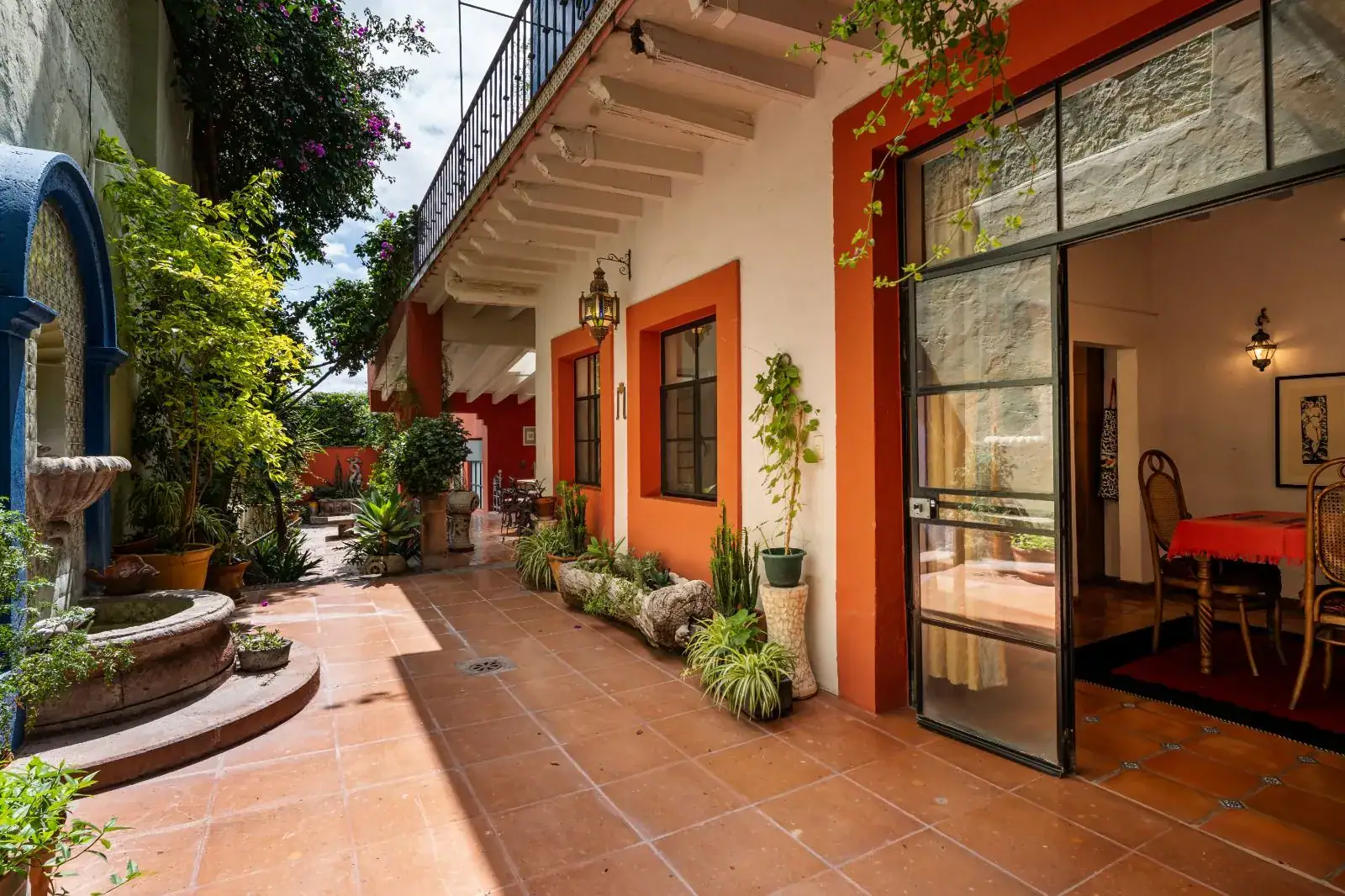 Casa Aldama, courtyard with a fountain and a red-framed steel glass door to a dining room, San Miguel de Allende