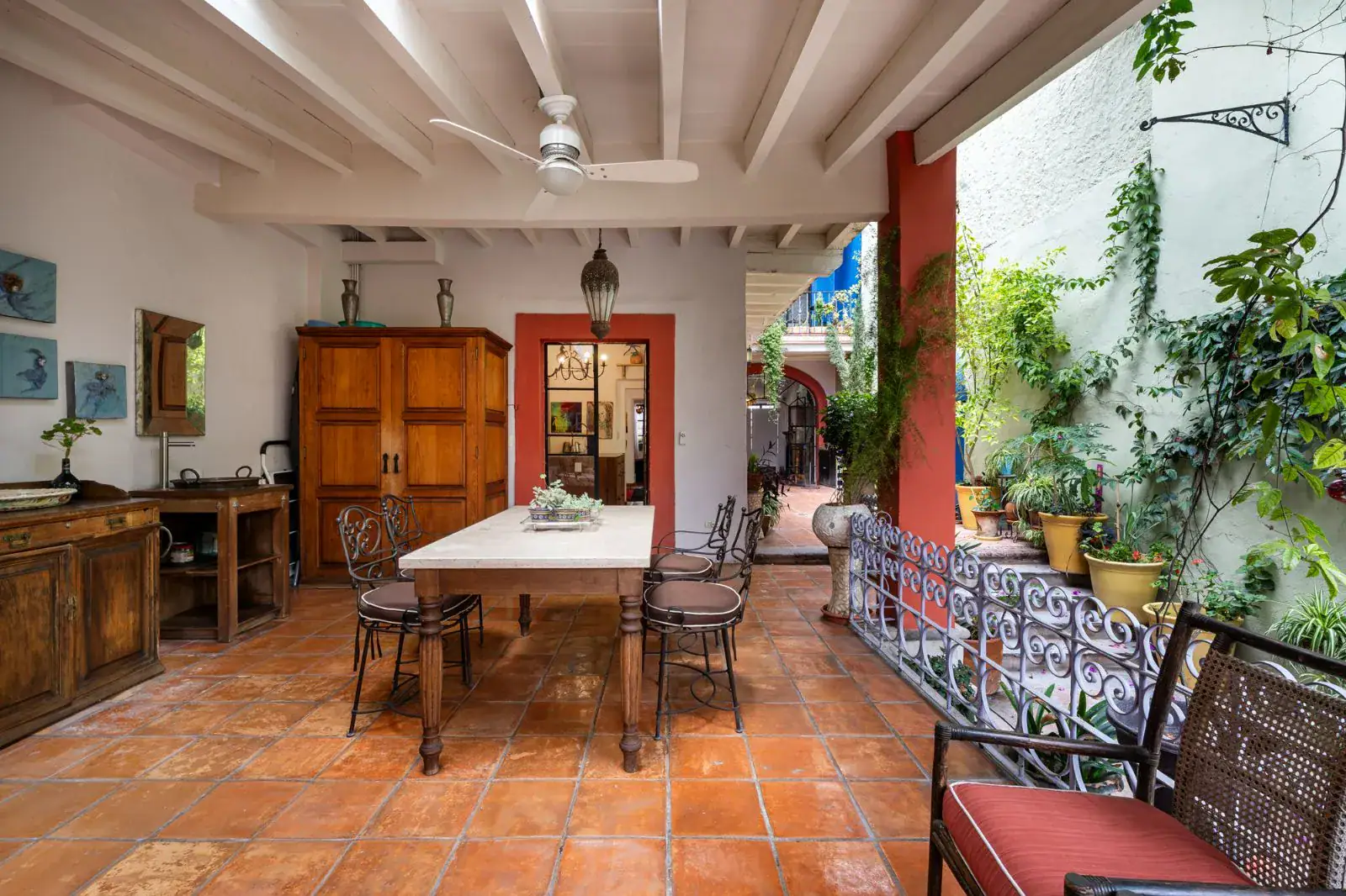 Casa Aldama, covered terrace with a long white dining table, a carved wood armoire and a view of the courtyard, San Miguel de Allende