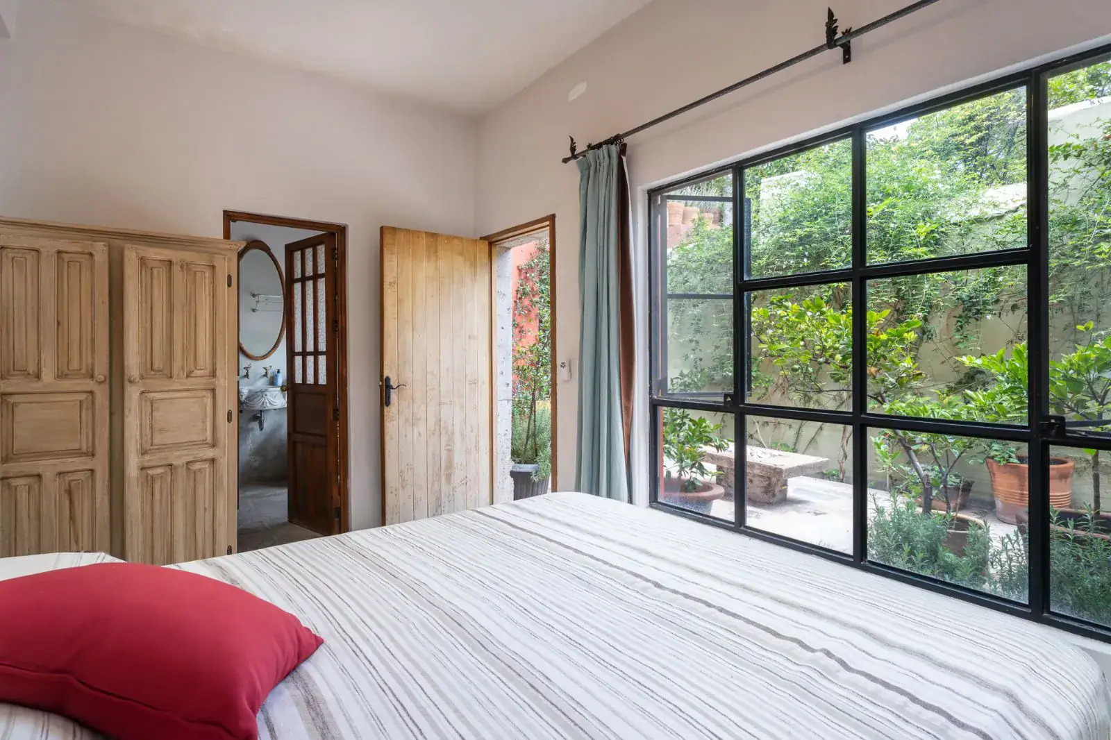 Casa Aldama, bedroom with a white bed, a large steel-framed window and a view of the garden, San Miguel de Allende
