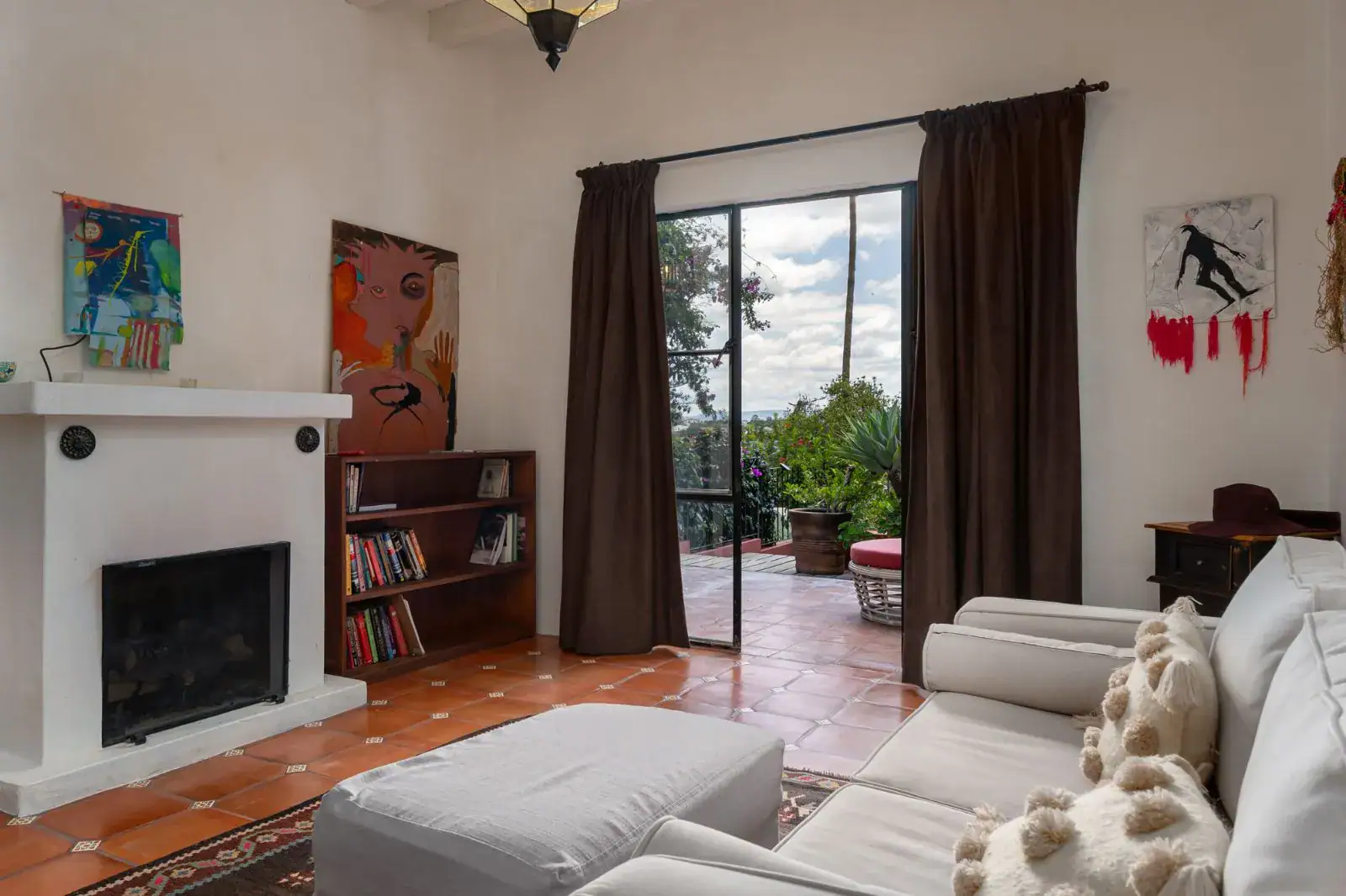 Casa Aldama, sitting room with a fireplace, bookshelf, white sofa and a door to the terrace, San Miguel de Allende