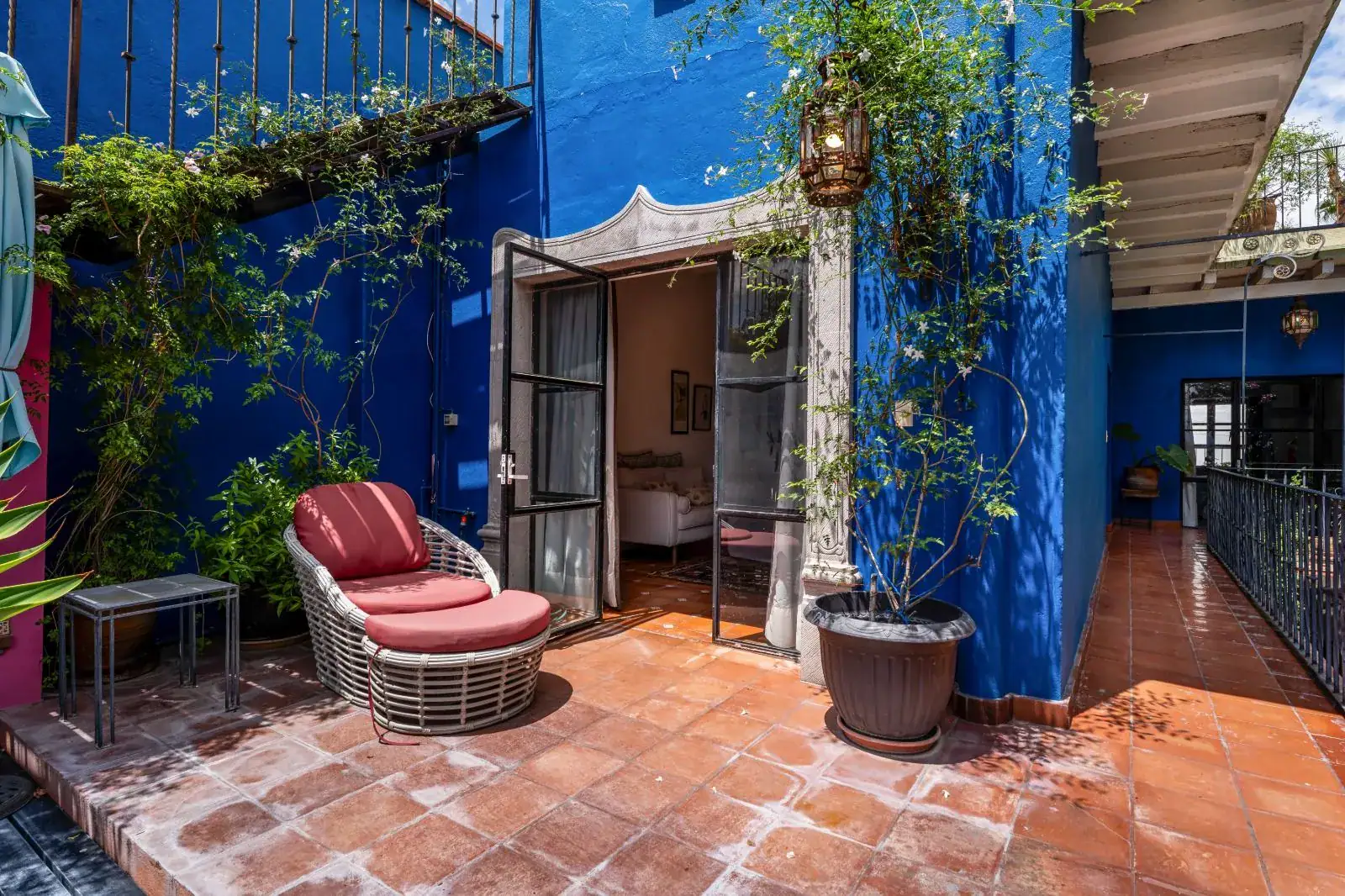 Casa Aldama, blue-walled terrace with a wicker lounge chair and a doorway to a bedroom, San Miguel de Allende