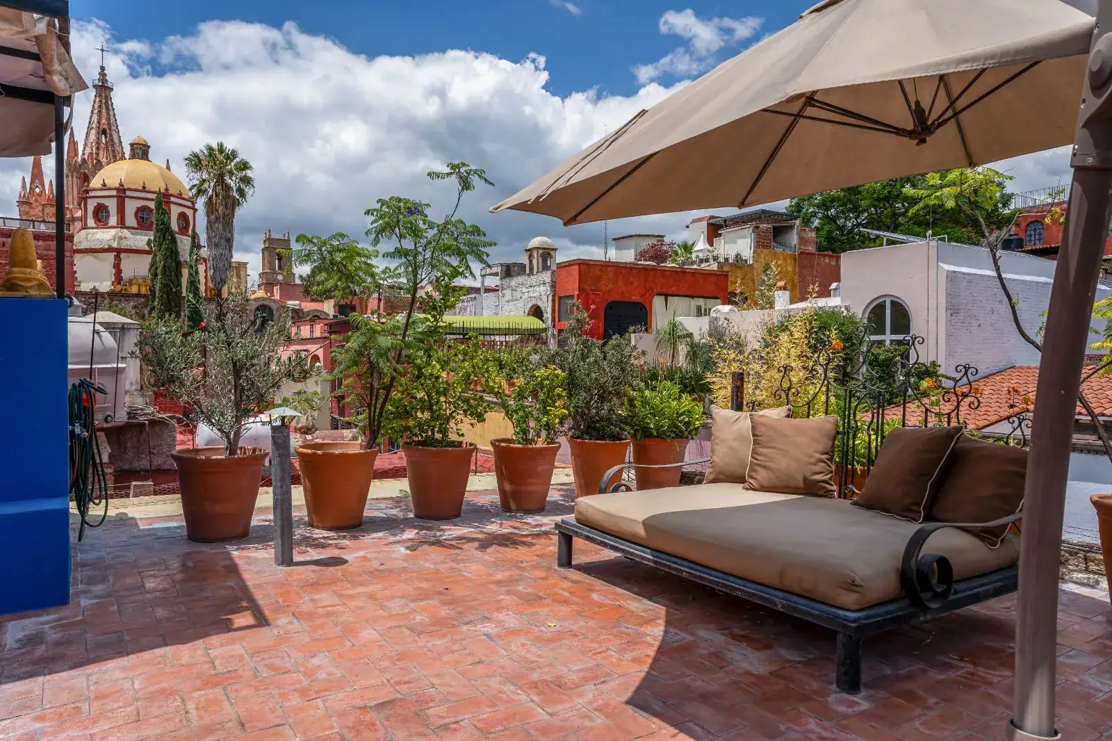 Casa Aldama, rooftop terrace with a daybed and an umbrella and a view of the Parroquia, San Miguel de Allende