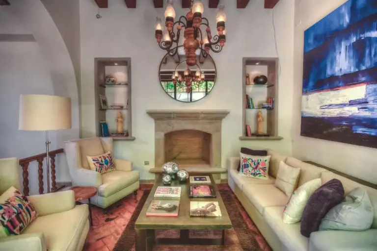 Casa Aldama, living room with a fireplace, cream sofas and a wrought-iron chandelier, San Miguel de Allende