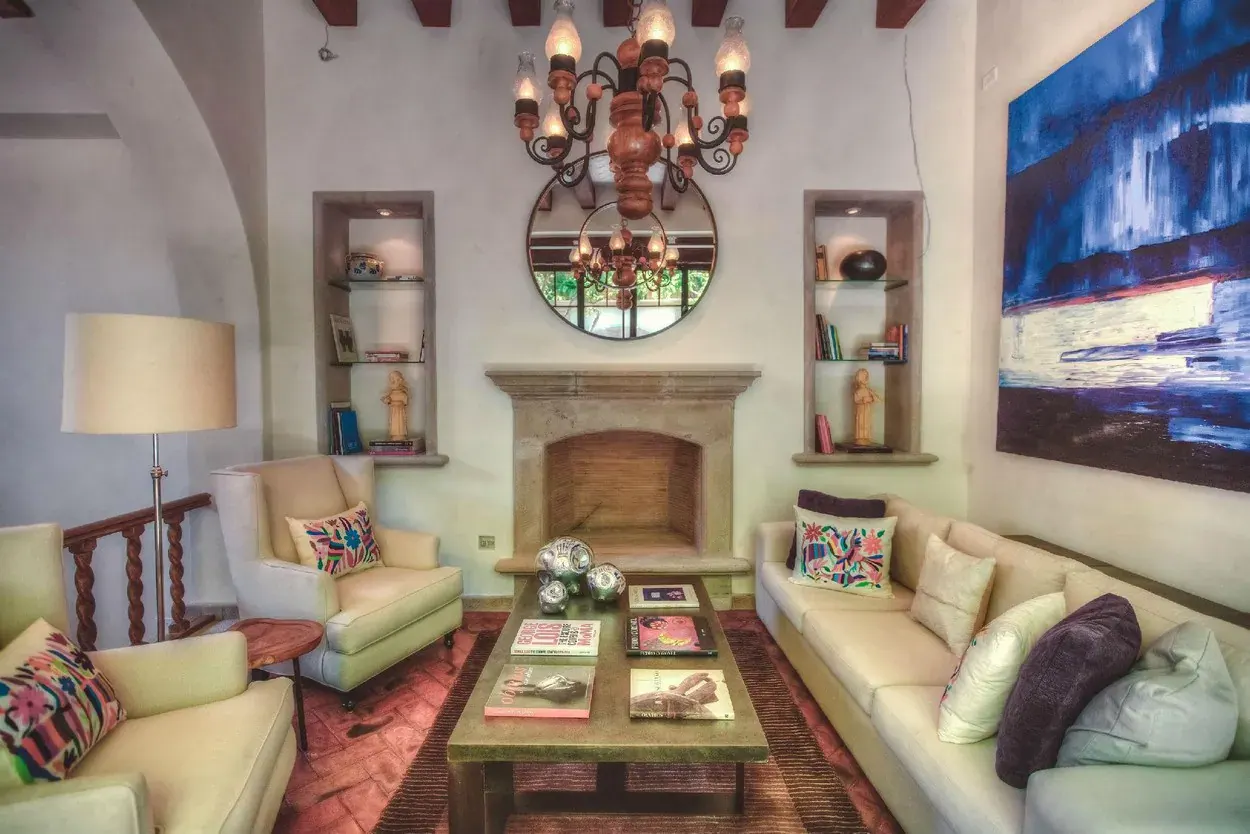 Casa Aldama, living room with a fireplace, cream sofas and a wrought-iron chandelier, San Miguel de Allende