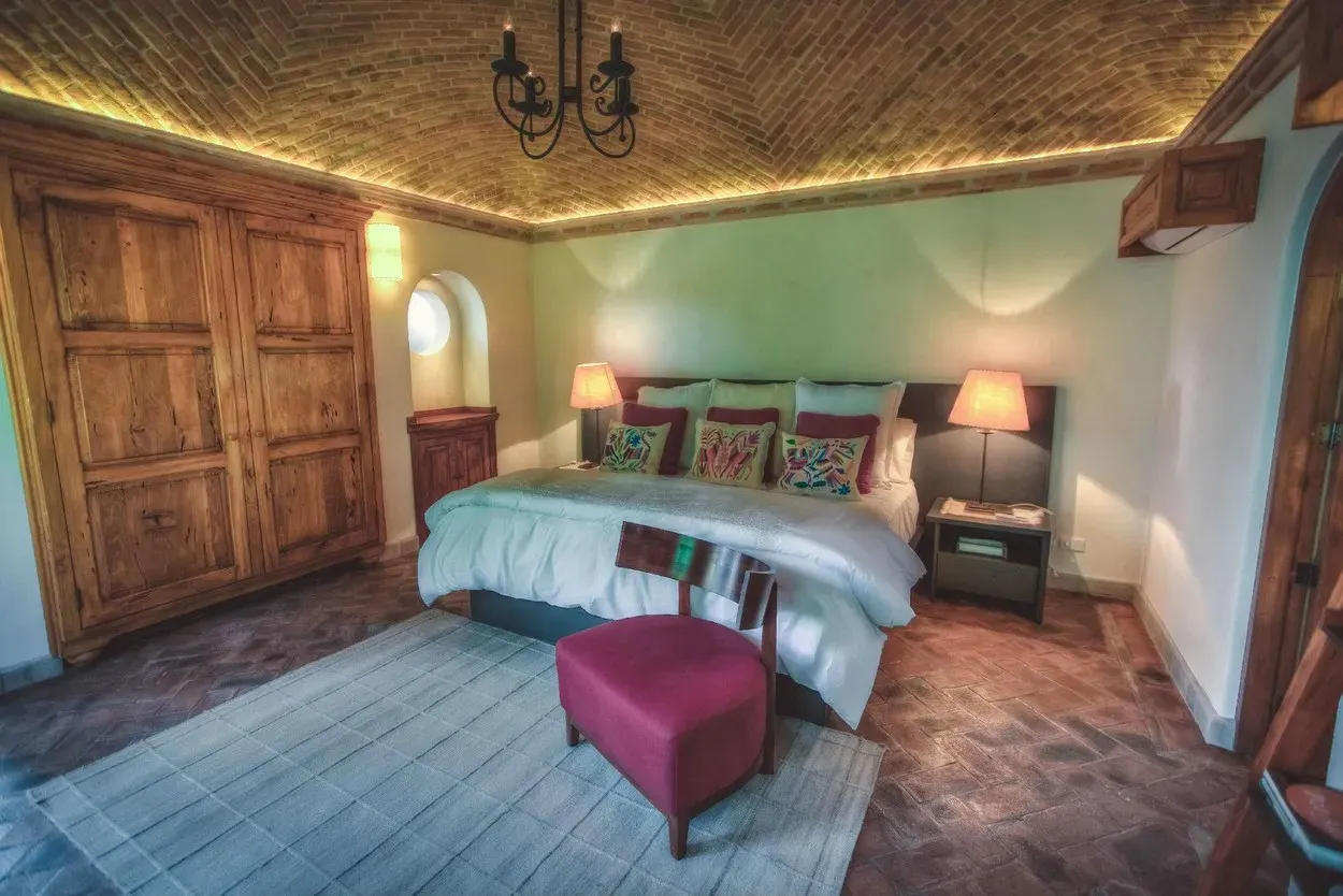 Casa Aldama, bedroom with a brick vaulted ceiling and a magenta bench, San Miguel de Allende