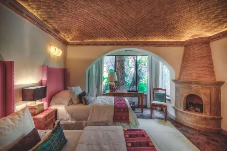 Casa Aldama, bedroom with a corner fireplace and a garden view, San Miguel de Allende