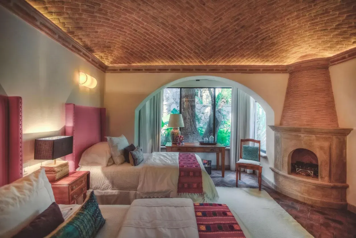 Casa Aldama, bedroom with a corner fireplace and a garden view, San Miguel de Allende