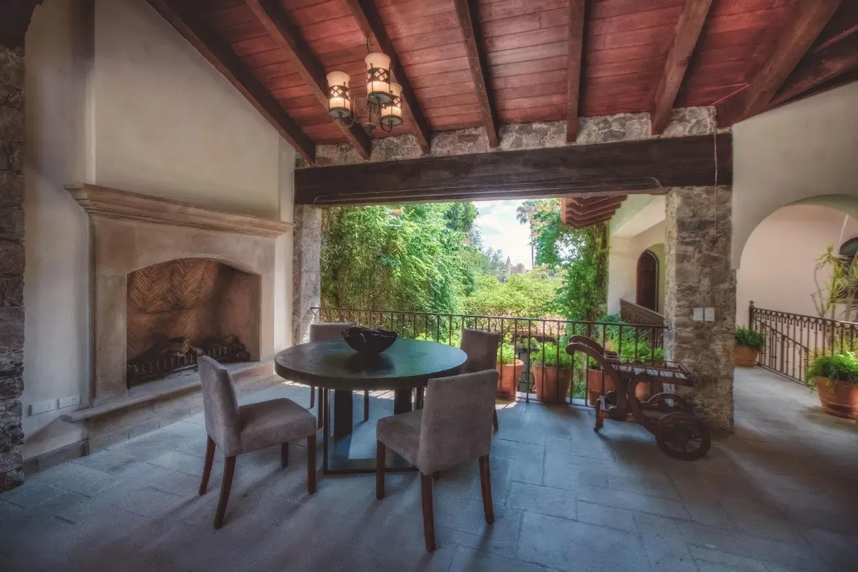 Casa Aldama, covered terrace with a stone fireplace and a dining table, San Miguel de Allende