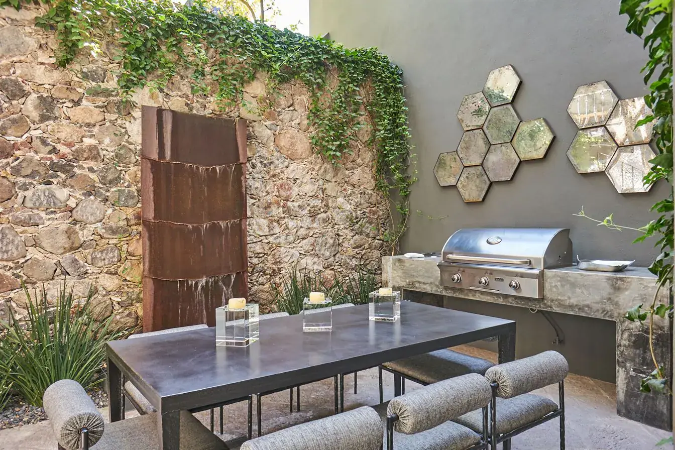 Casa Arcadia, garden dining table beside a stone wall with an outdoor grill, San Miguel de Allende