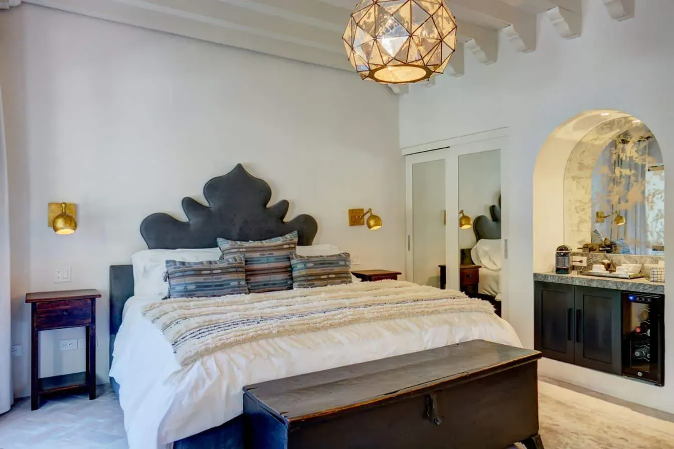 Casa Arcadia, primary bedroom with a carved headboard and a geometric pendant light, San Miguel de Allende