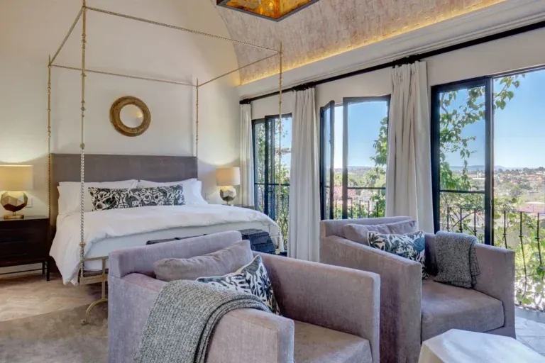 Casa Arcadia, canopy bed and sitting area with a view through tall windows, San Miguel de Allende