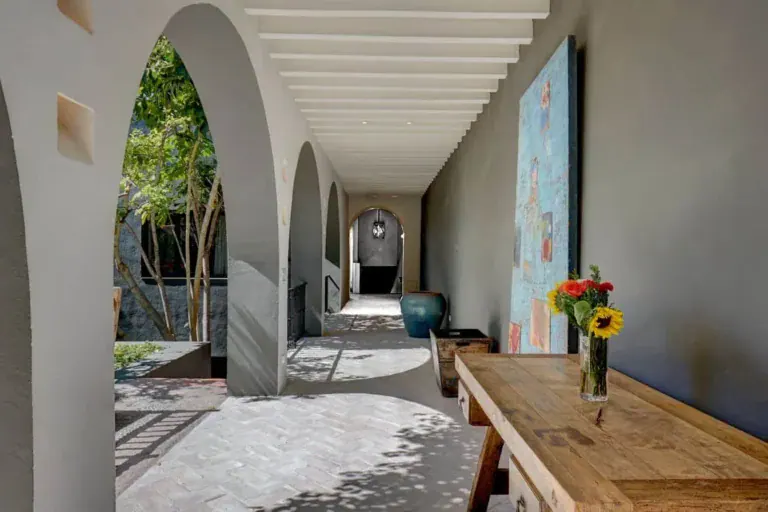 Casa Arcadia, arched corridor with white beams and a wood table, San Miguel de Allende