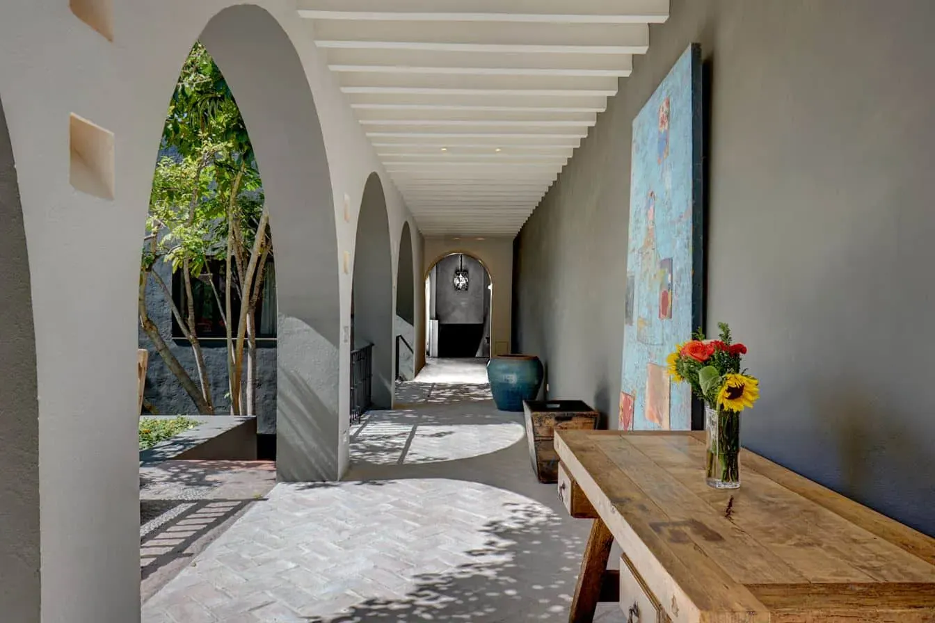 Casa Arcadia, arched corridor with white beams and a wood table, San Miguel de Allende