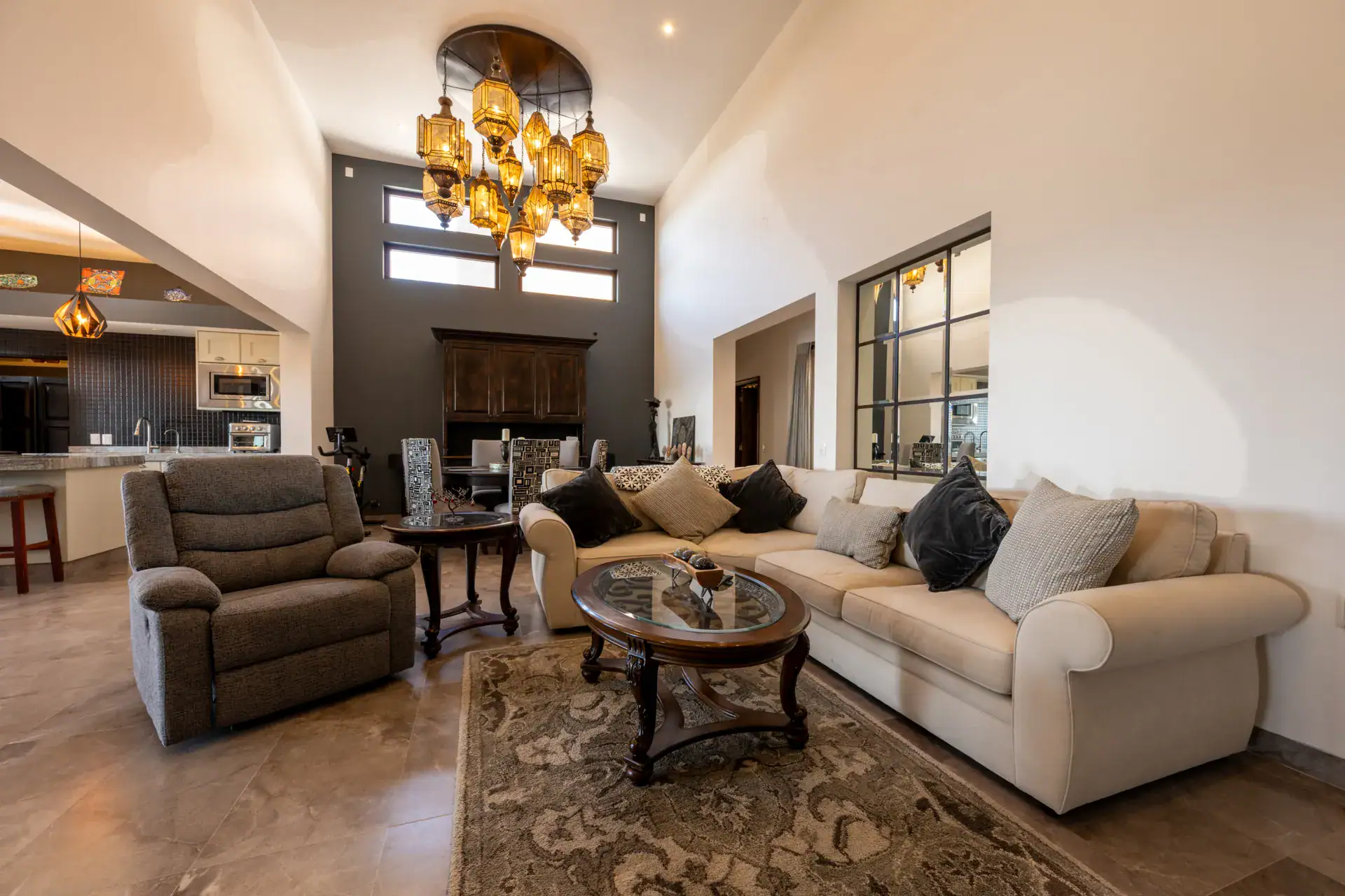 Casa Atardecer, double-height living area with a cream sectional, a recliner, a coffee table and a cluster of amber pendant lights, San Miguel de Allende