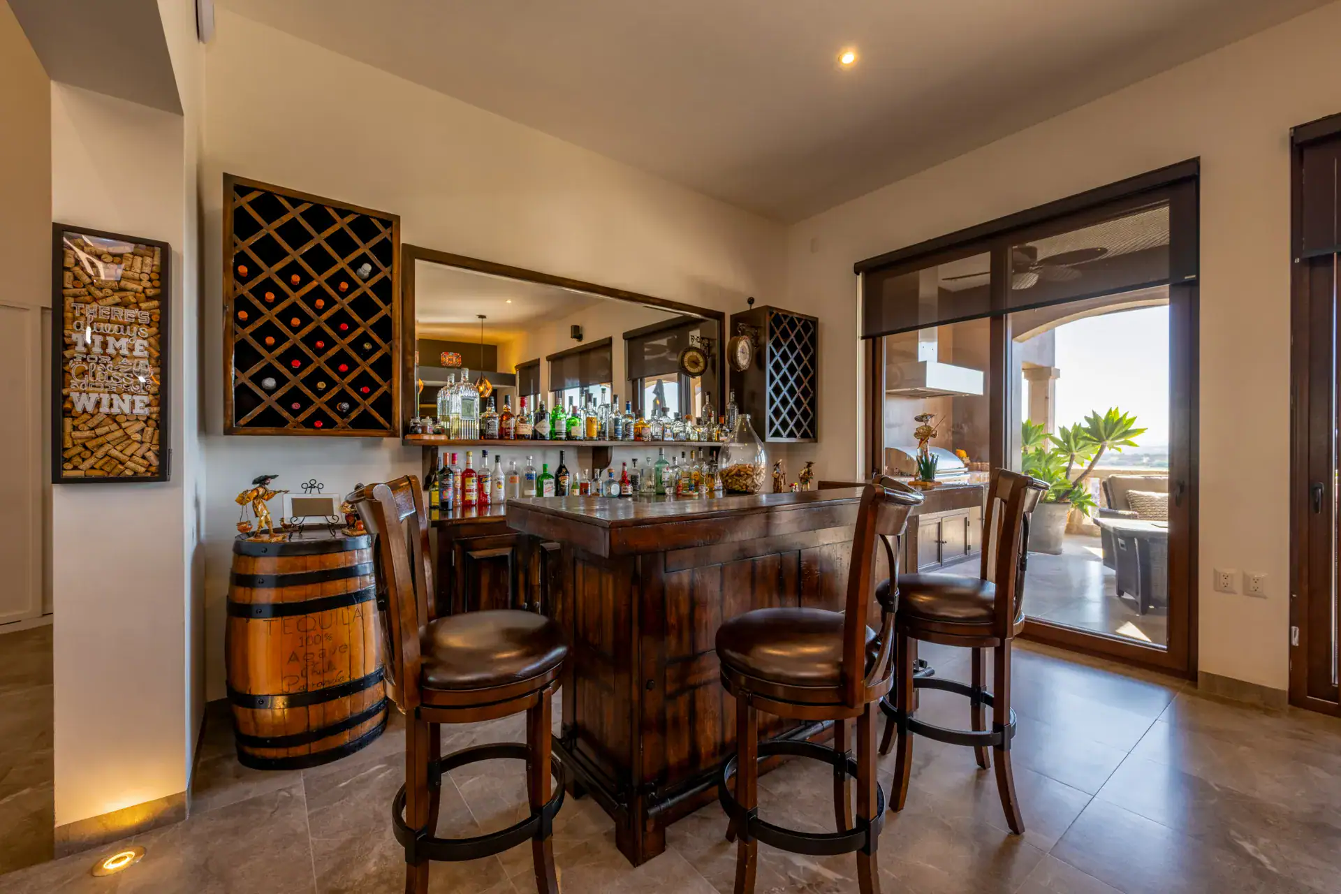 Casa Atardecer, home bar with wood stools, a wine rack, a wine barrel and a sliding glass door to the terrace, San Miguel de Allende