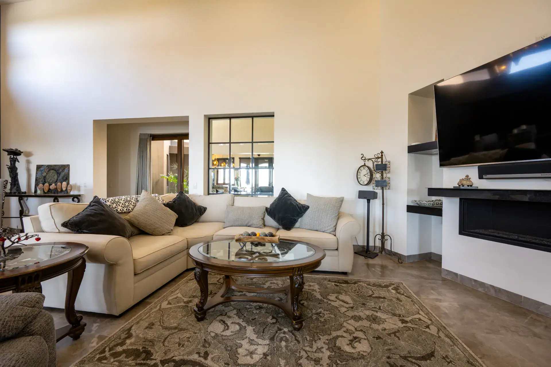 Casa Atardecer, living room with a cream sectional, a wall television above a linear fireplace and a patterned rug, San Miguel de Allende