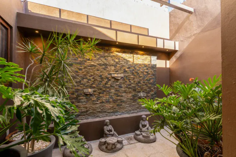Casa Atardecer, interior courtyard with a stone wall fountain, tropical plants and small Buddha statues, San Miguel de Allende