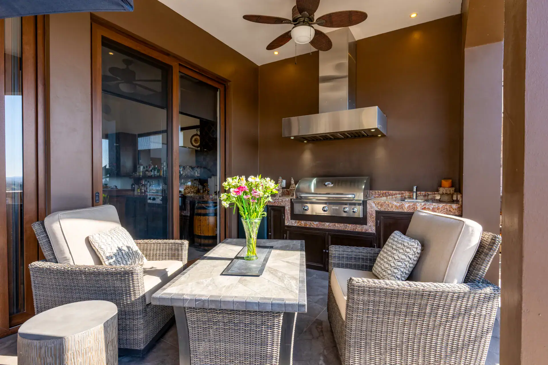 Casa Atardecer, covered terrace lounge with wicker chairs, a stone table and a stainless grill under a ceiling fan, San Miguel de Allende