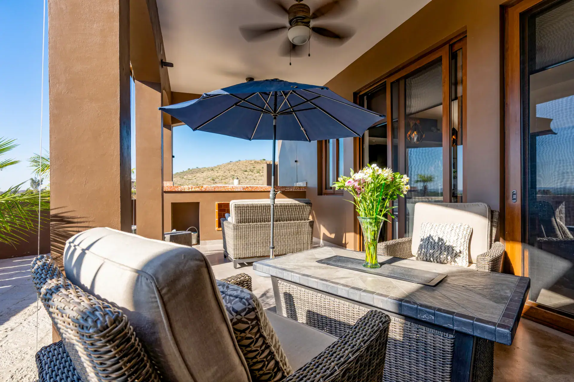 Casa Atardecer, terrace with wicker furniture, a navy umbrella and a fire table with a view of the hills, San Miguel de Allende