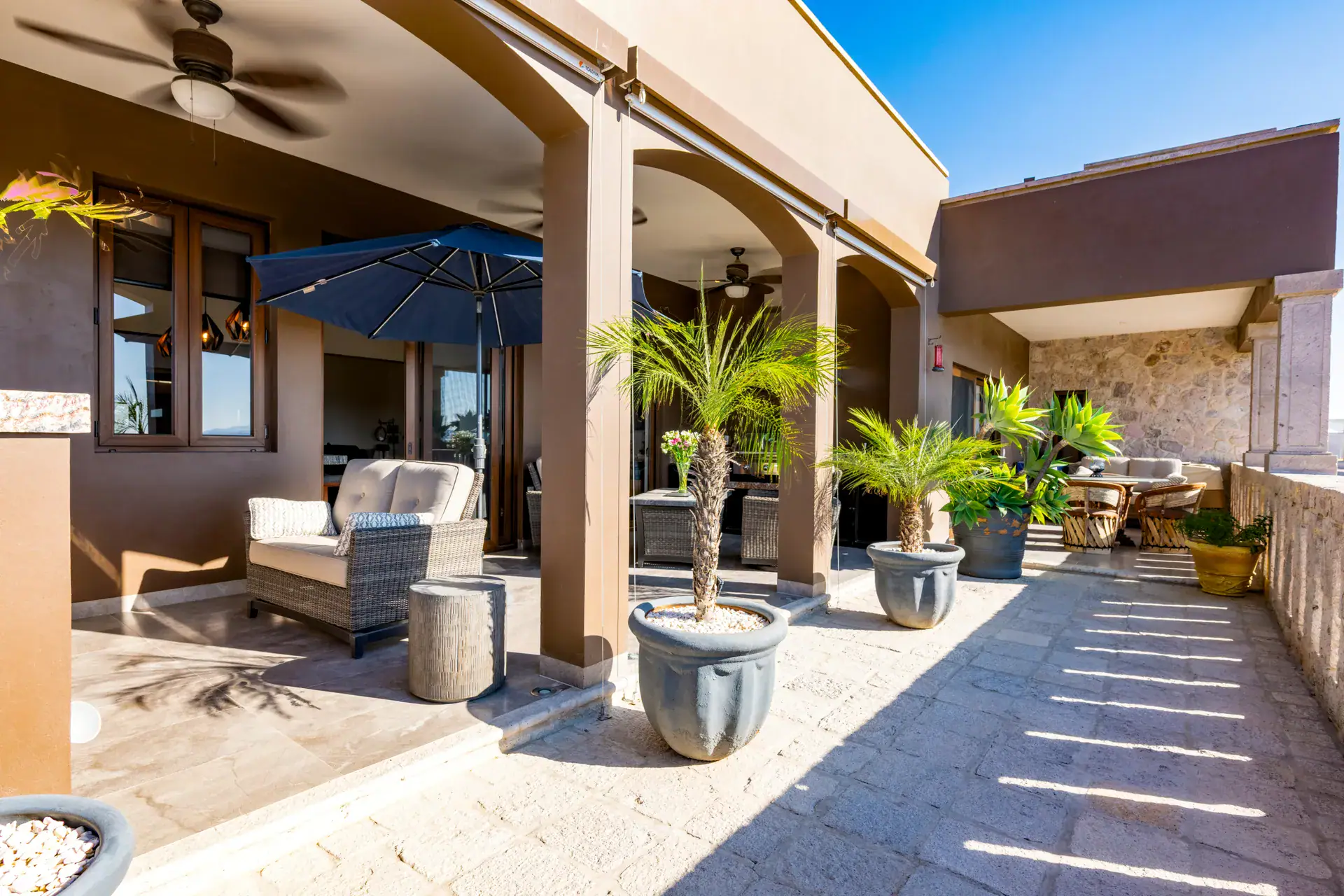 Casa Atardecer, terrace with wicker furniture, potted palms, a stone paved floor and arches, San Miguel de Allende