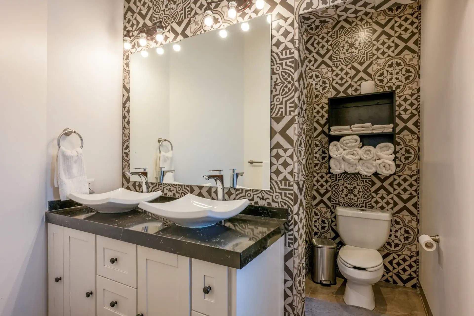 Casa Atardecer, bathroom with a double vanity with two white vessel sinks, a black and white patterned tile wall and a lit mirror, San Miguel de Allende