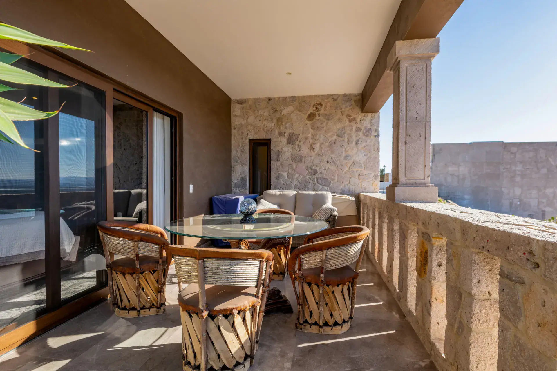 Casa Atardecer, balcony with a glass table, four equipale leather chairs, a stone balustrade and a view from the bedroom, San Miguel de Allende