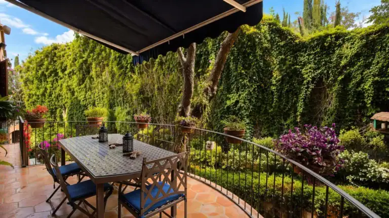 Casa Baeza, balcony dining table with blue cushioned chairs overlooking a green garden wall, San Miguel de Allende