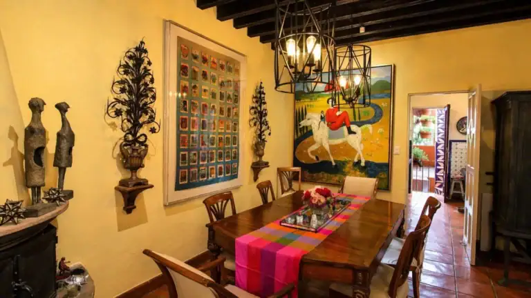 Casa Baeza, dining room with a wood table, pink striped runner, iron chandeliers and a colorful horse painting, San Miguel de Allende