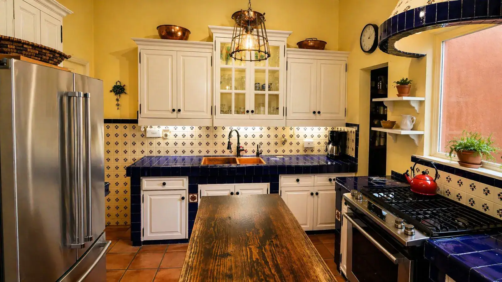 Casa Baeza, kitchen with white cabinets, blue tile counters, a stainless refrigerator and a wood-topped island, San Miguel de Allende