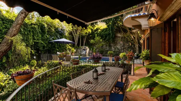 Casa Baeza, balcony dining table above a garden pool under an awning, San Miguel de Allende