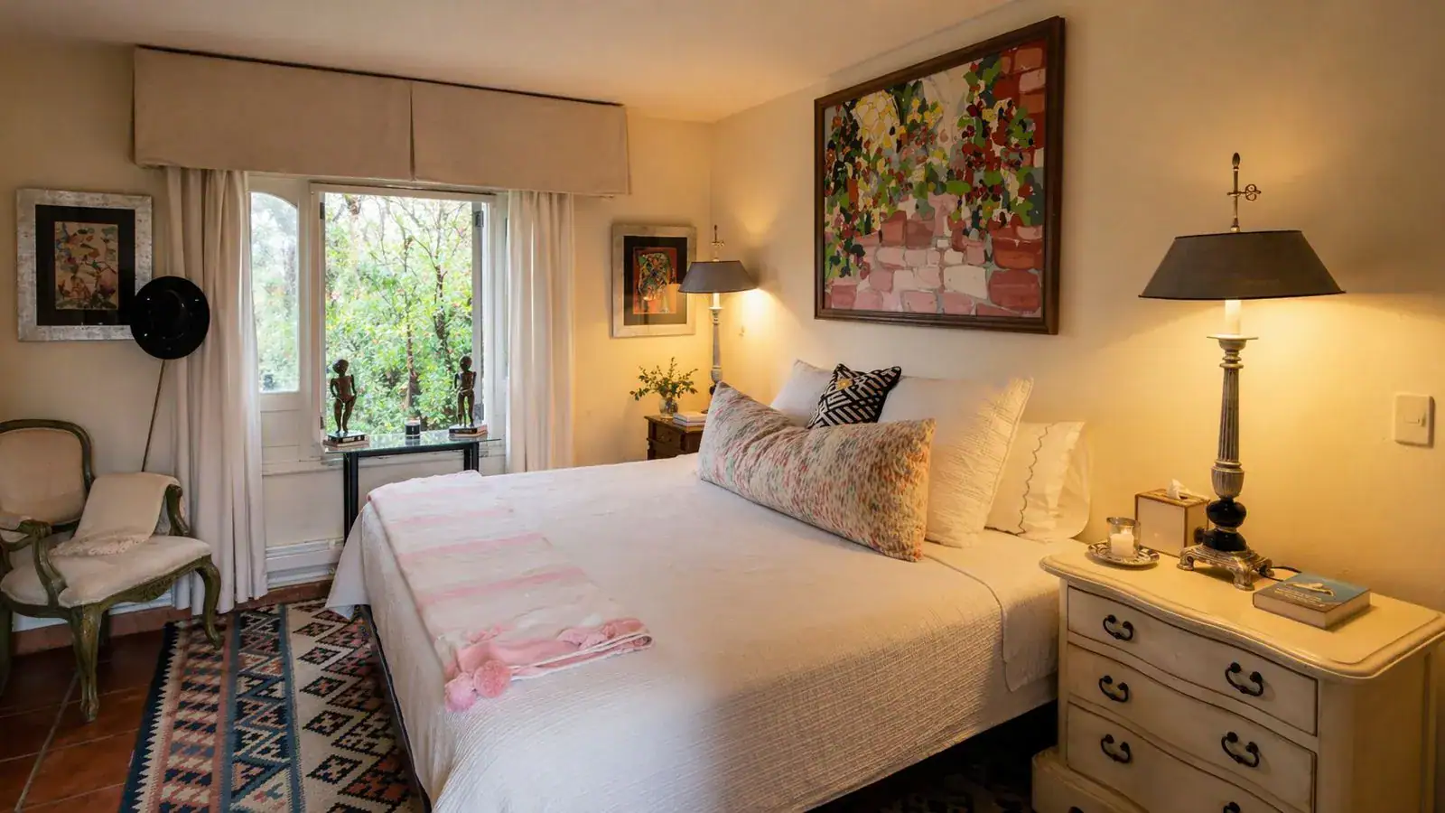 Casa Baeza, bedroom with a white bed, wood nightstands, a colorful painting and garden windows, San Miguel de Allende