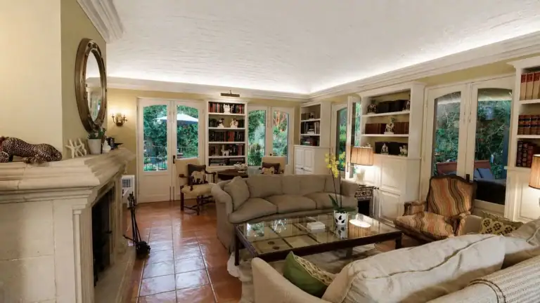 Casa Baeza, living room with a stone fireplace, cream sofas, built-in bookshelves and French doors, San Miguel de Allende