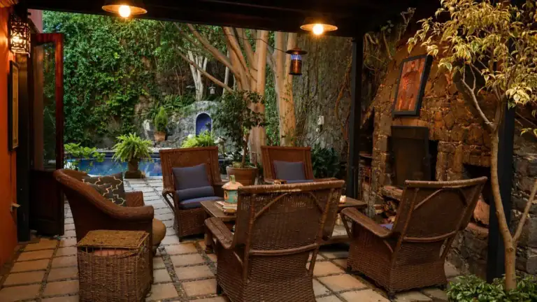 Casa Baeza, covered patio with wicker armchairs, a stone wall and a view to the pool, San Miguel de Allende