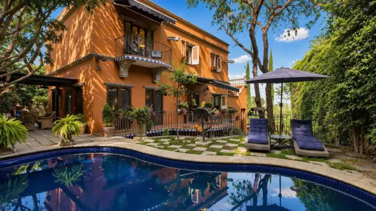 Casa Baeza, orange two-story house with a curved pool, lounge chairs and an umbrella, San Miguel de Allende