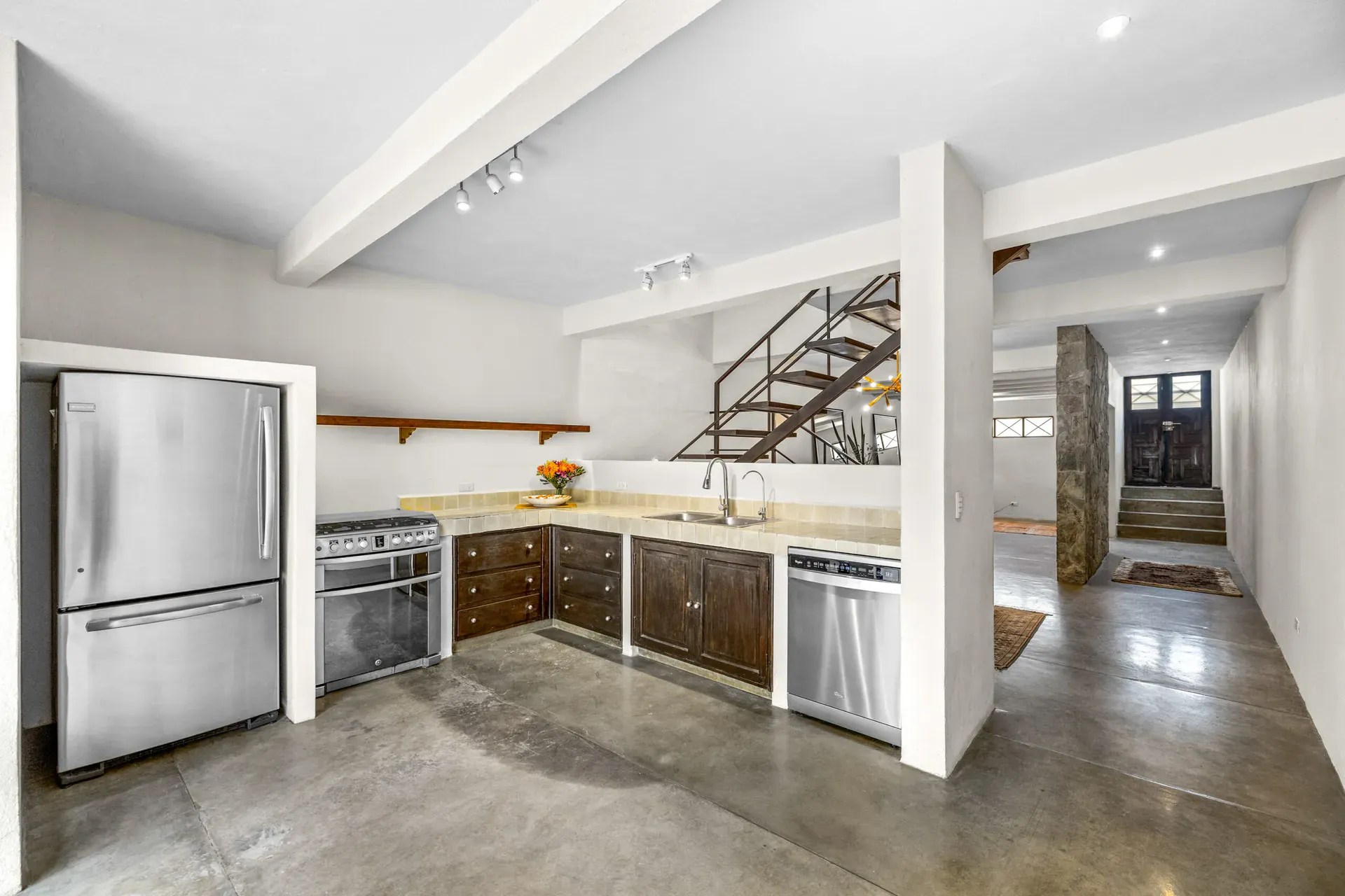 Casa Beatrice, kitchen with a stainless refrigerator, a range, a dishwasher, wood cabinets and the entry hall beyond, San Miguel de Allende