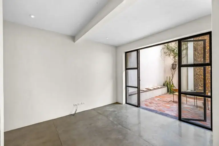 Casa Beatrice, empty room with a polished concrete floor and a steel-framed sliding glass door to the courtyard, San Miguel de Allende