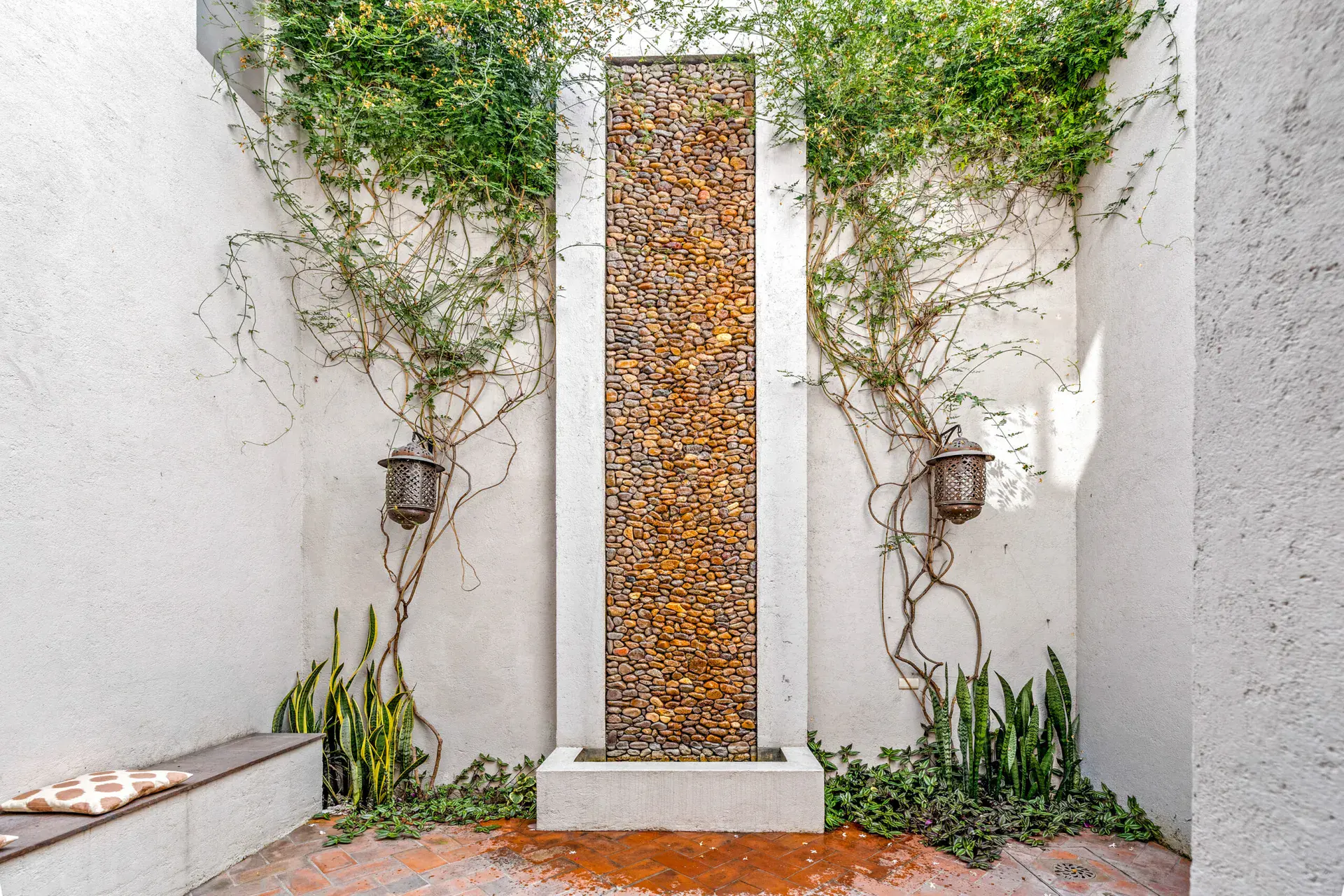 Casa Beatrice, courtyard fountain wall of pebbles with climbing vines, two lanterns and a built-in bench, San Miguel de Allende