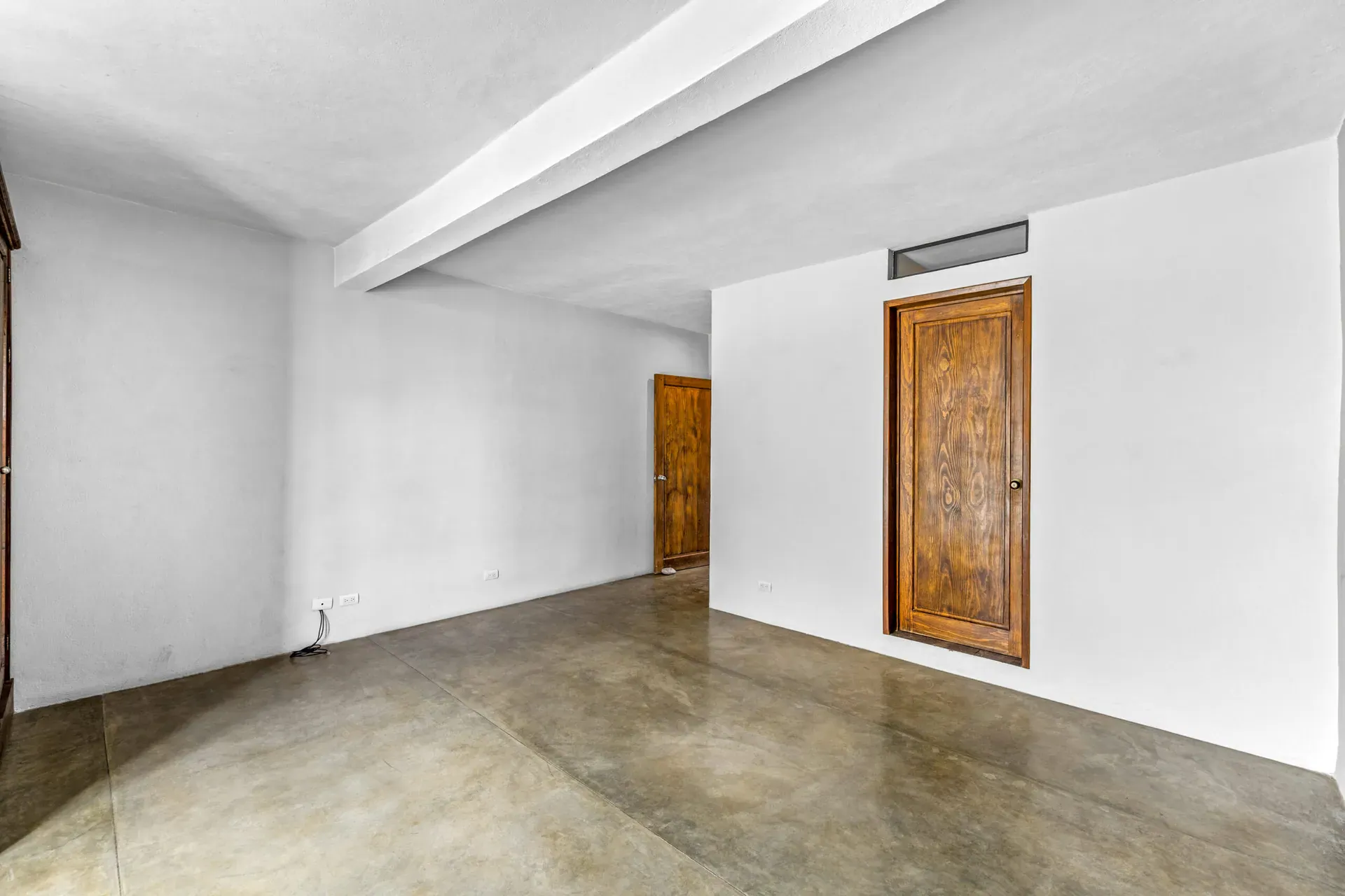 Casa Beatrice, empty bedroom with a carved wood door and a tan wall, San Miguel de Allende