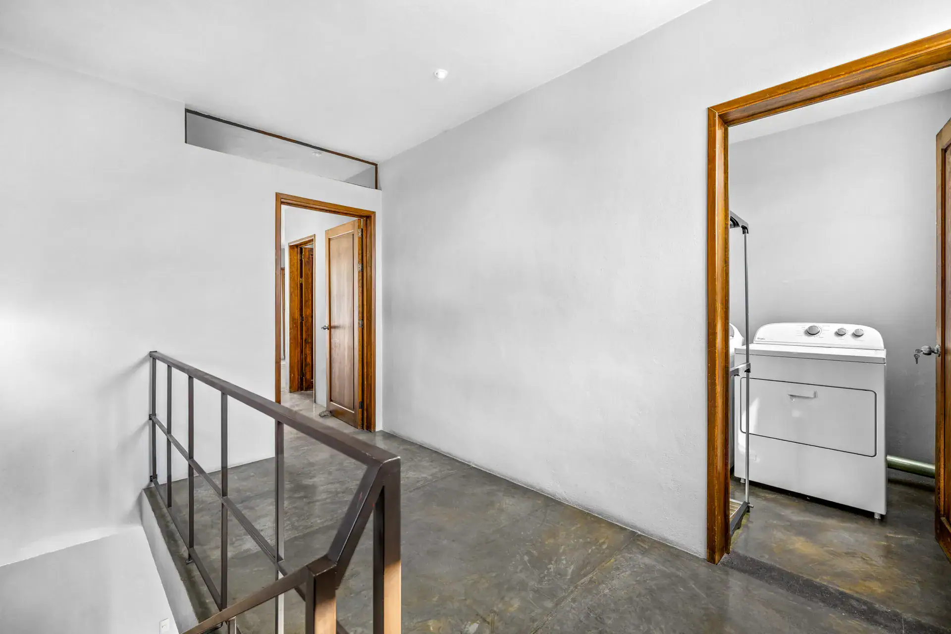 Casa Beatrice, upstairs hall with a steel railing, a washer and dryer and a carved wood door, San Miguel de Allende