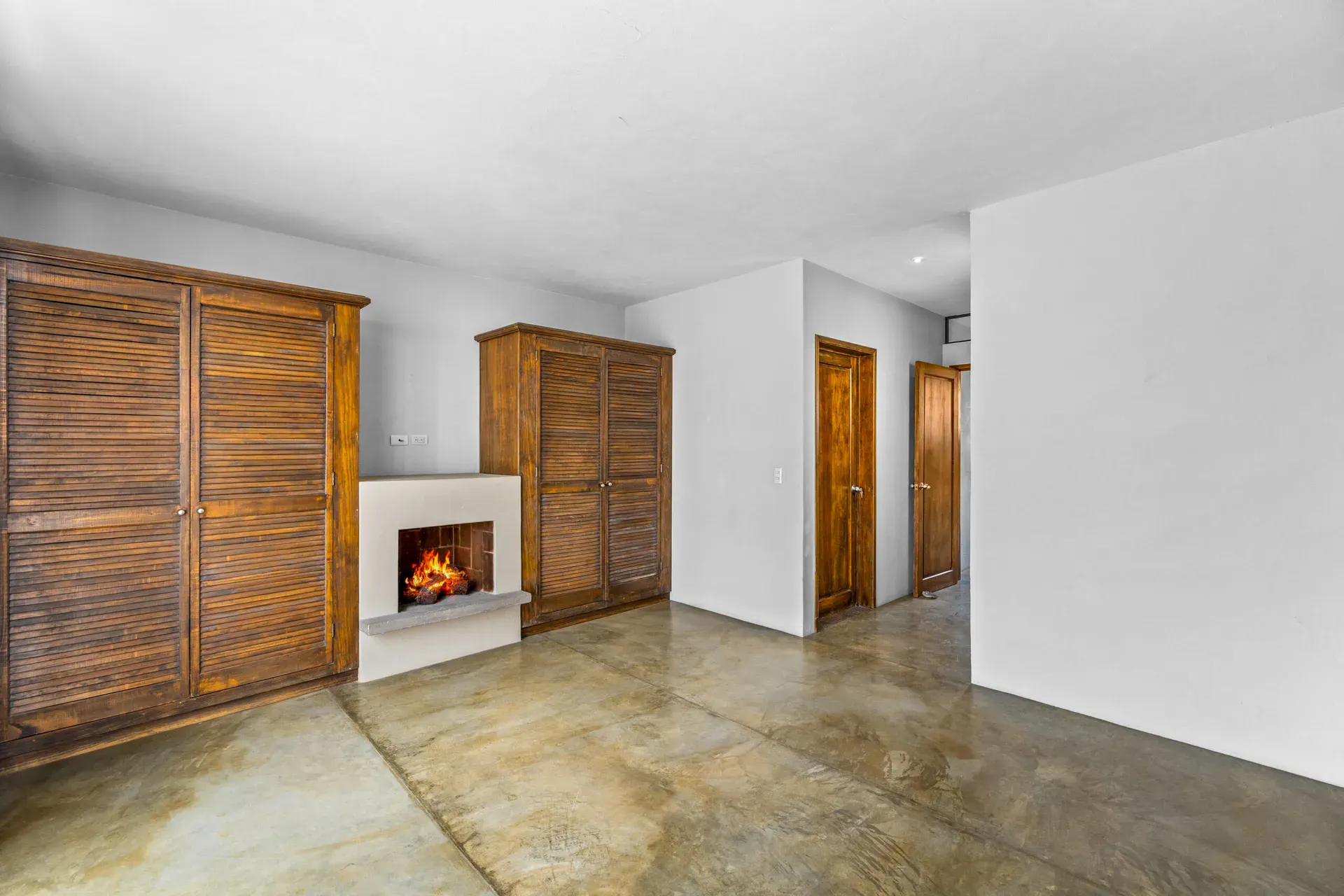 Casa Beatrice, empty bedroom with a fireplace, louvered wood wardrobes and a doorway, San Miguel de Allende