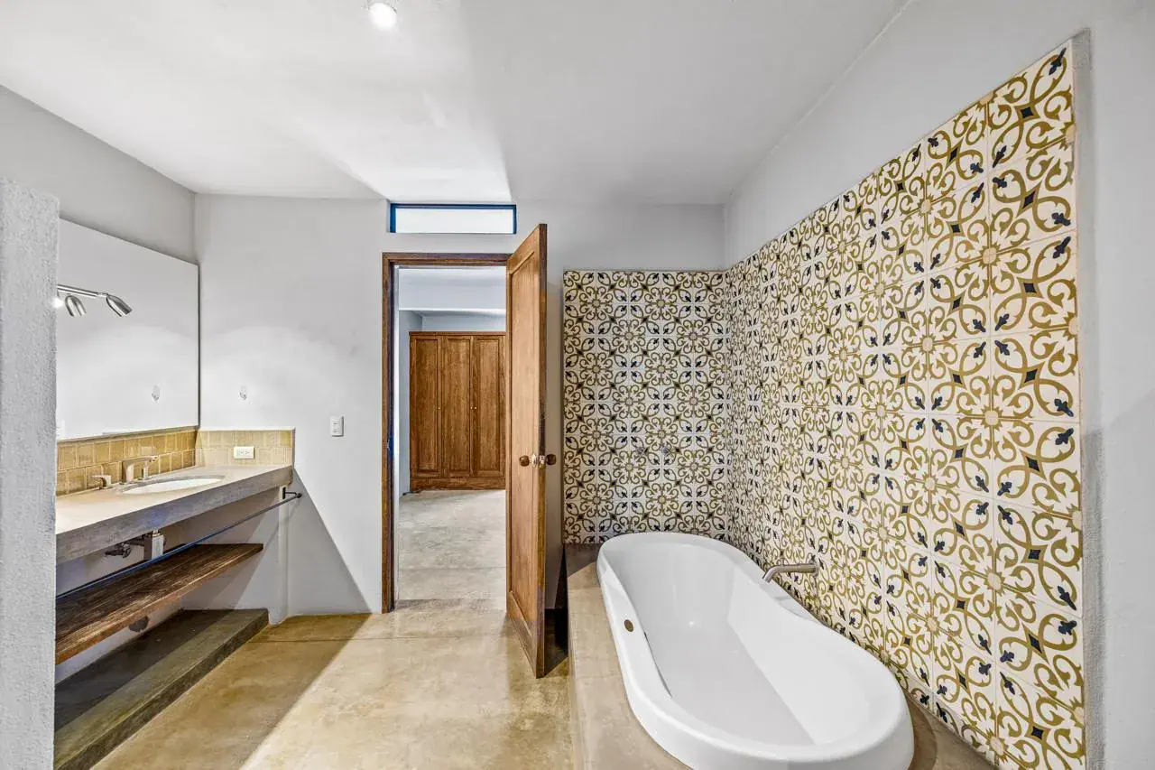 Casa Beatrice, bathroom with a freestanding tub, a yellow and gray patterned tile wall and a double vanity, San Miguel de Allende