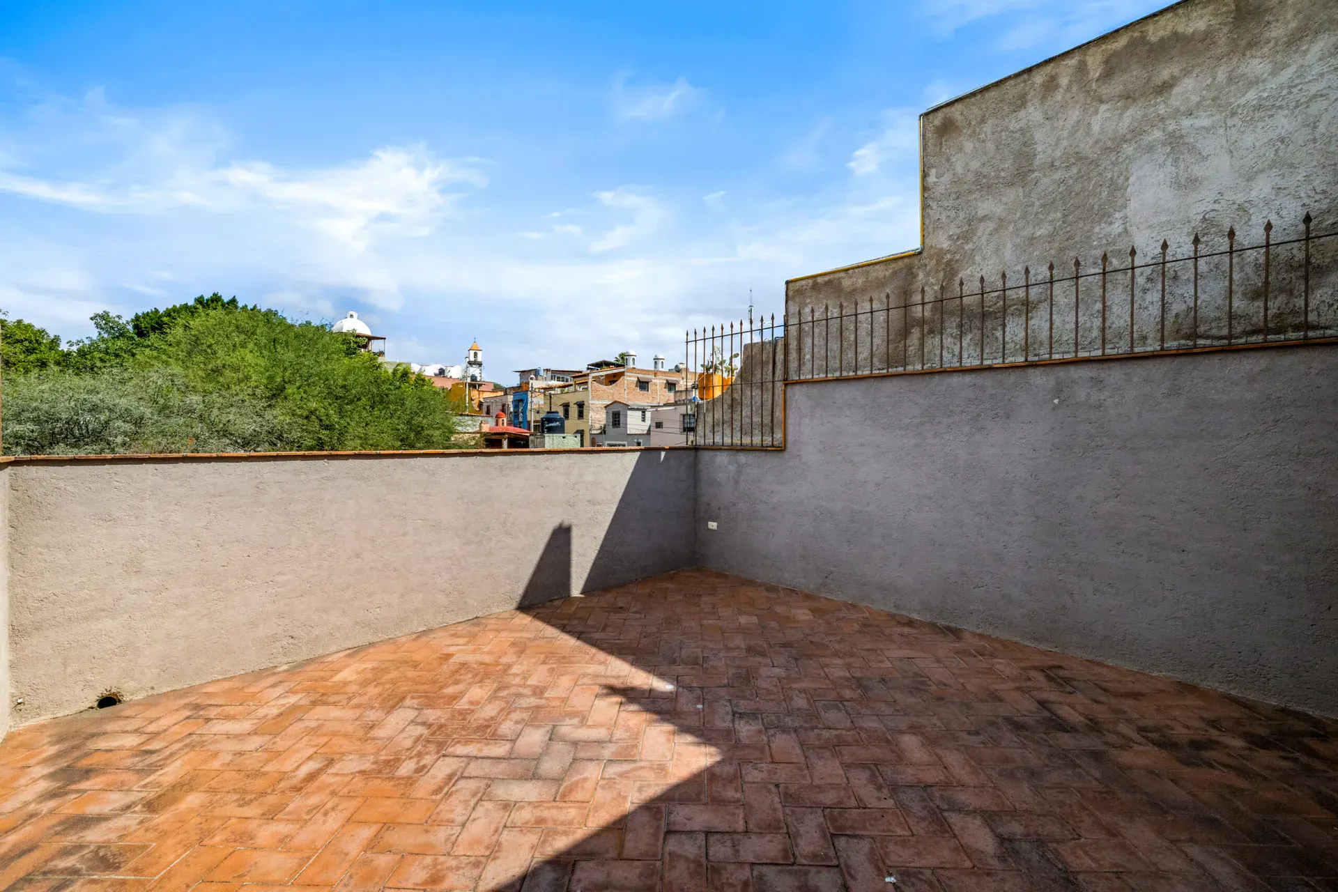 Casa Beatrice, empty roof terrace with a herringbone terracotta floor, high walls and views of rooftops, San Miguel de Allende