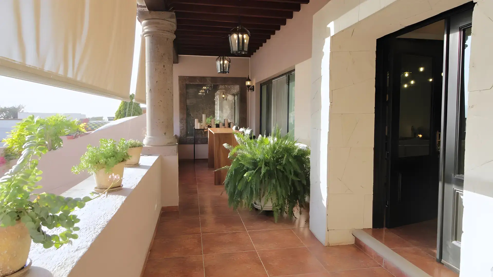 Casa Bellavista, covered gallery with stone columns, potted ferns and a tile floor, San Miguel de Allende